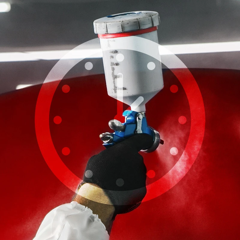Gloved hand using a spray gun to apply colorcoat to a red vehicle panel.
