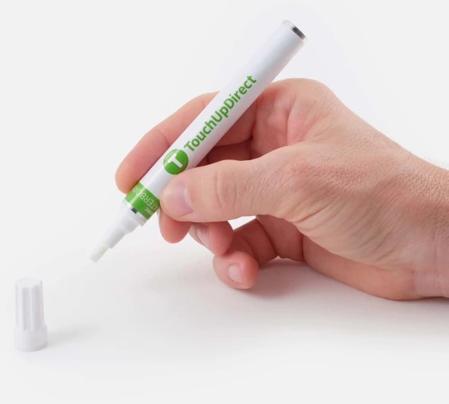 Hand using a TouchUpDirect paint pen for a small automotive paint repair