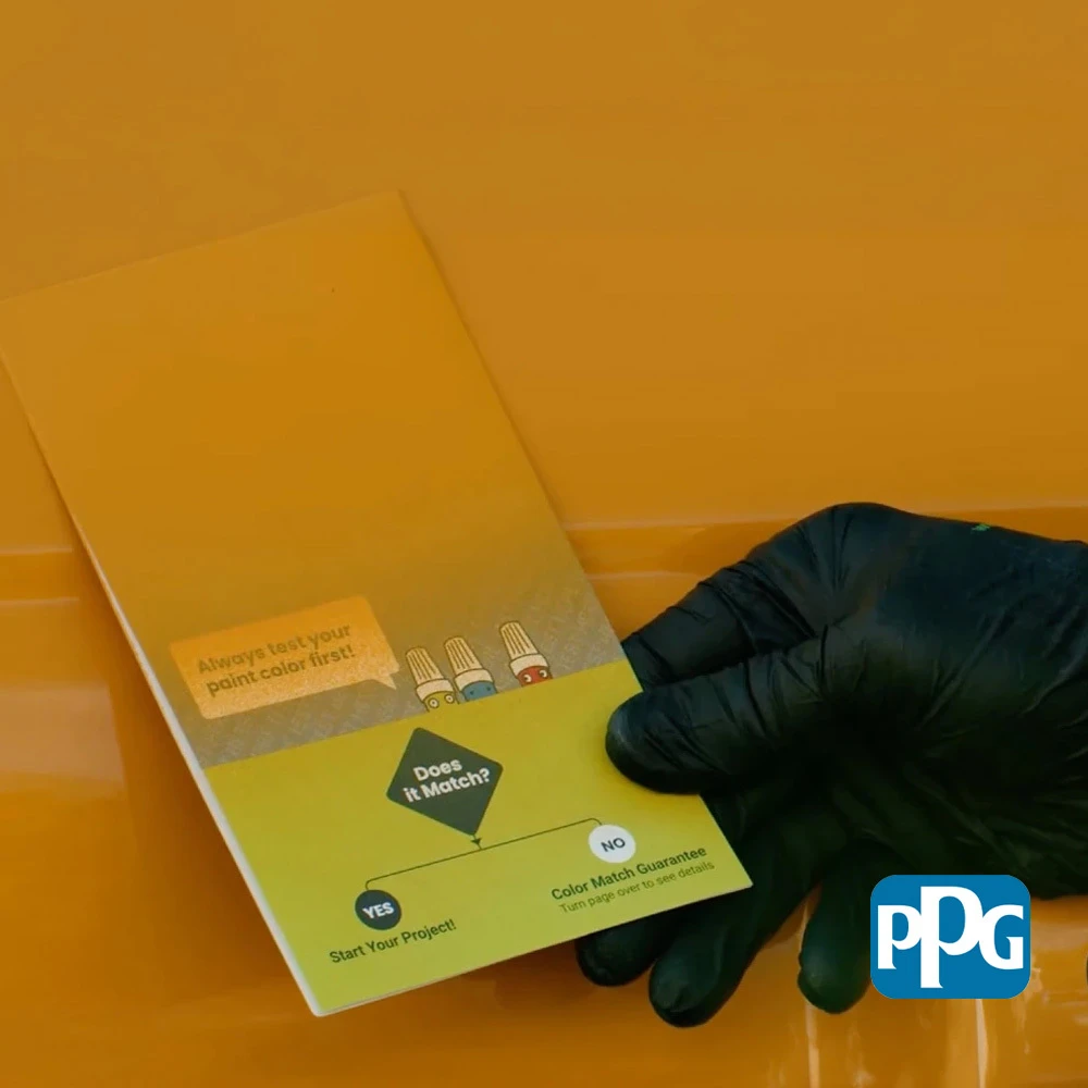 Gloved hand comparing painted test cards under different lighting angles