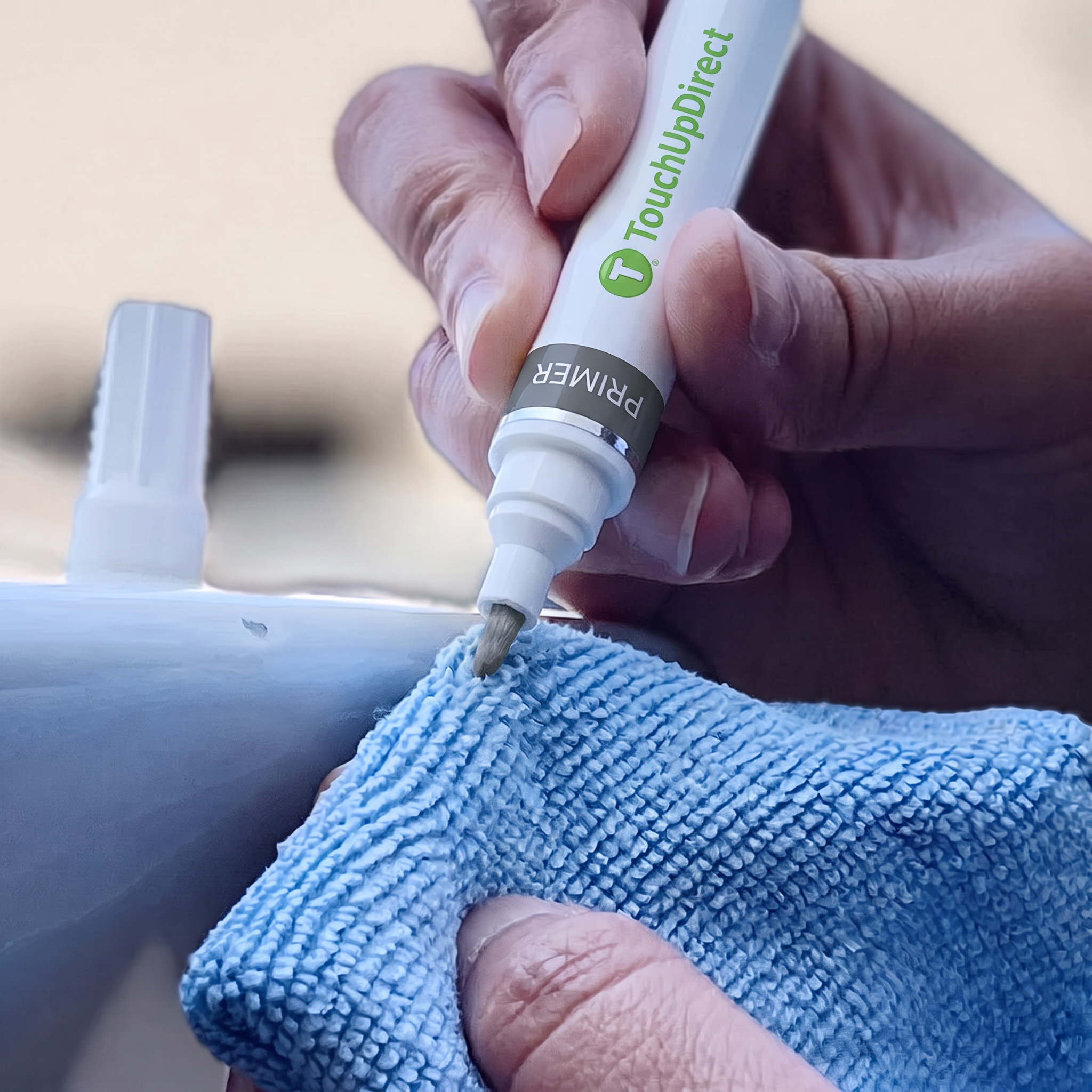 Hand priming the tip of a TouchUpDirect paint pen against a microfiber cloth.