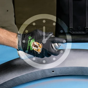 Gloved hand applying automotive primer with a clock graphic representing primer drying time