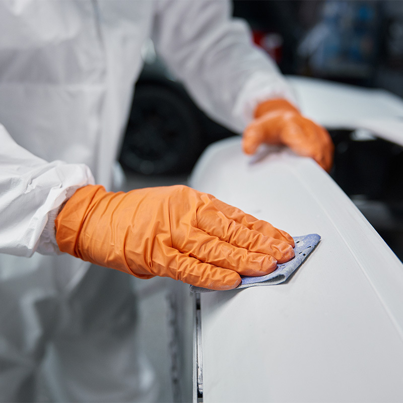 Person preparing an automotive surface with a sanding block
