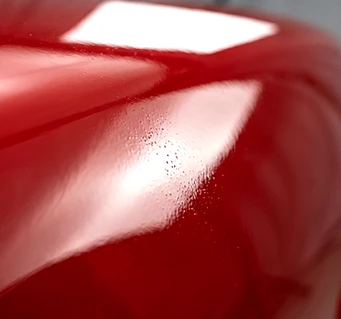 Close-up of bubbling and surface defects in red automotive paint applied before the primer dried