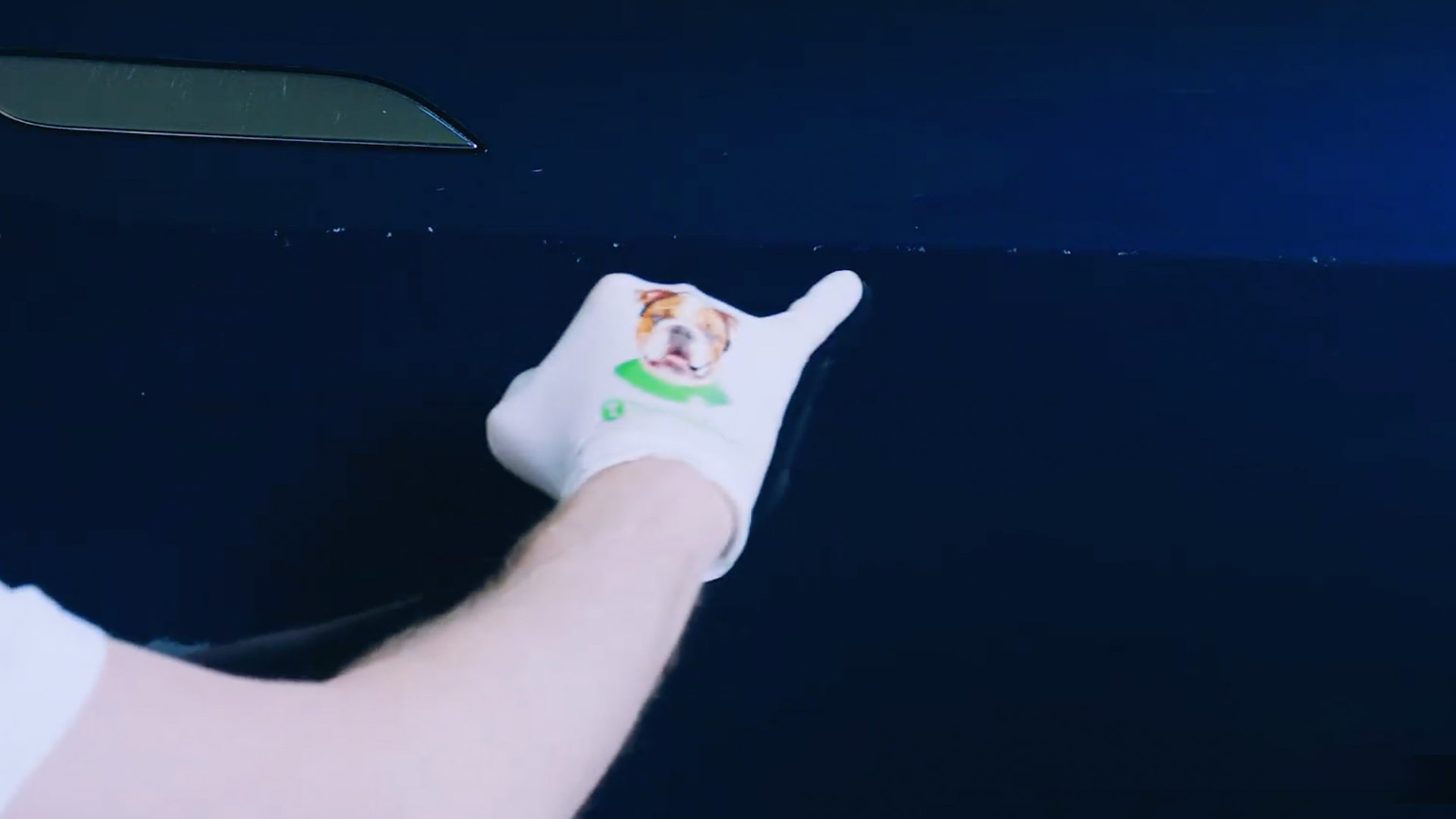 Gloved hand indicating multiple small rock chips on a dark blue vehicle panel.
