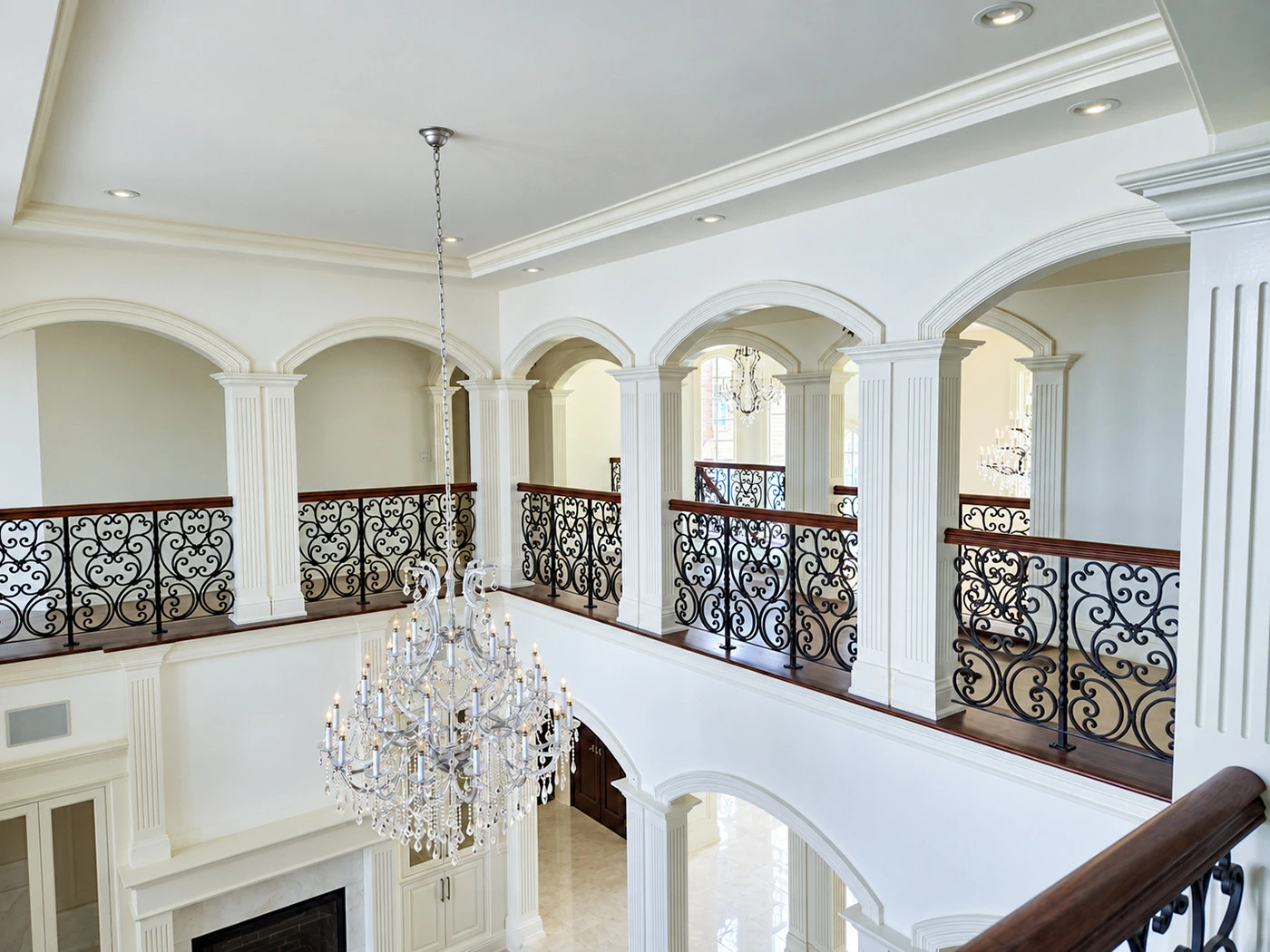 Multiple custom radius arches with white moulding and fluted columns in a two-story interior