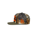 Stilly Boys Clinch hat, left side view with orange embroidered bucking bronc rider outline on hardwoods camo