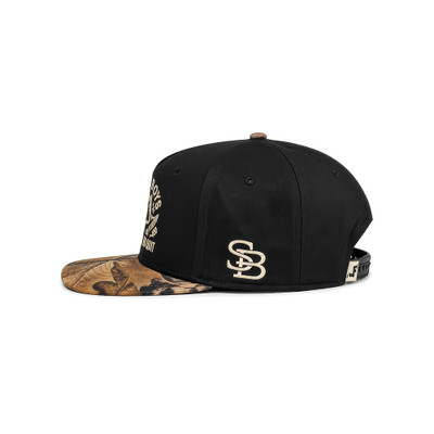 Stilly Boys Dirt Grit No Quit hat in black, back view showing adjustable rubber snap strap closure