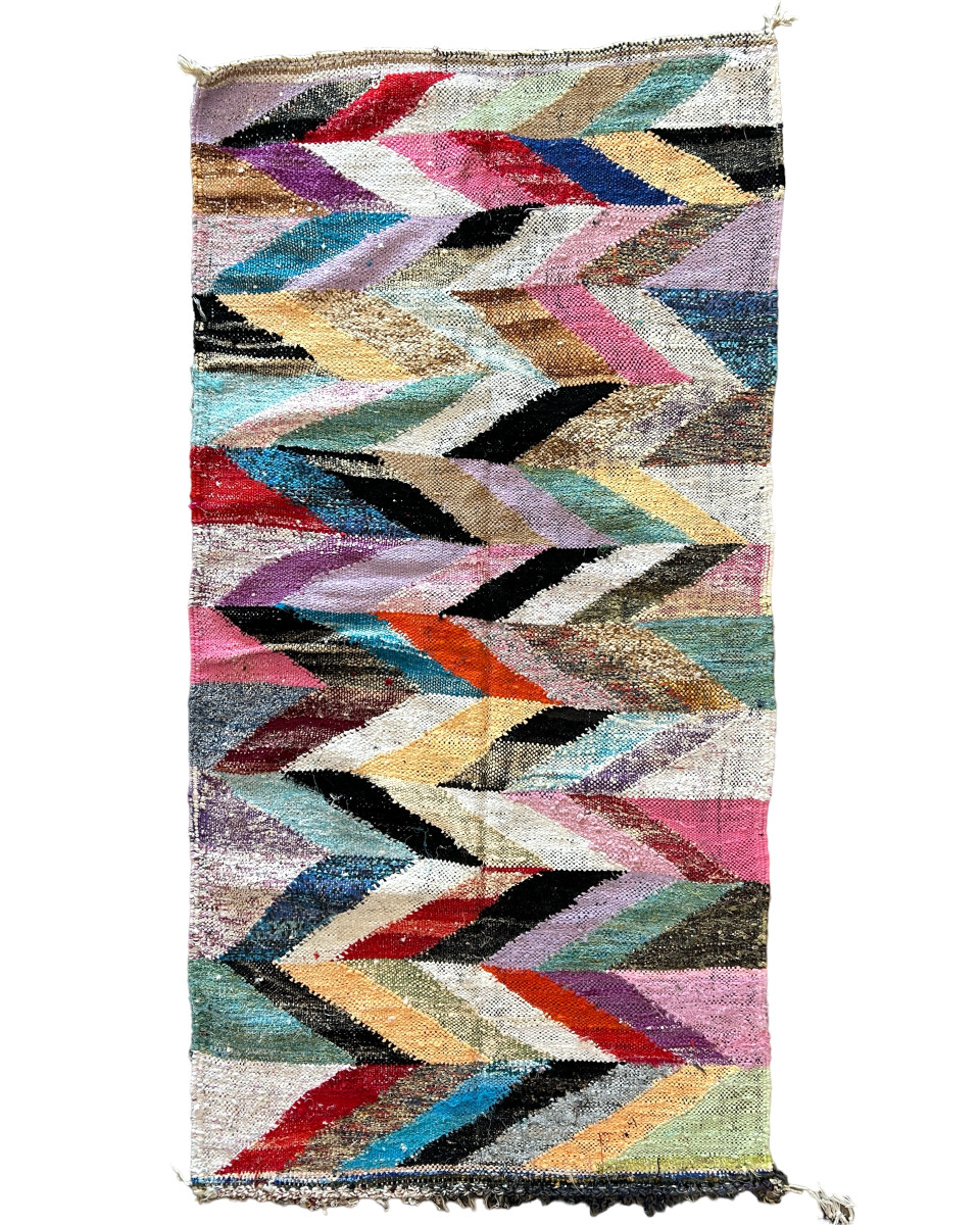 Handwoven rag rug with a dynamic zig zag pattern from weavers in southern Morocco. Beautiful on the floor or on the wall. A medly of colors. Tied fringe at one end. 3ft  x 6 ft 4"  Cotton blend