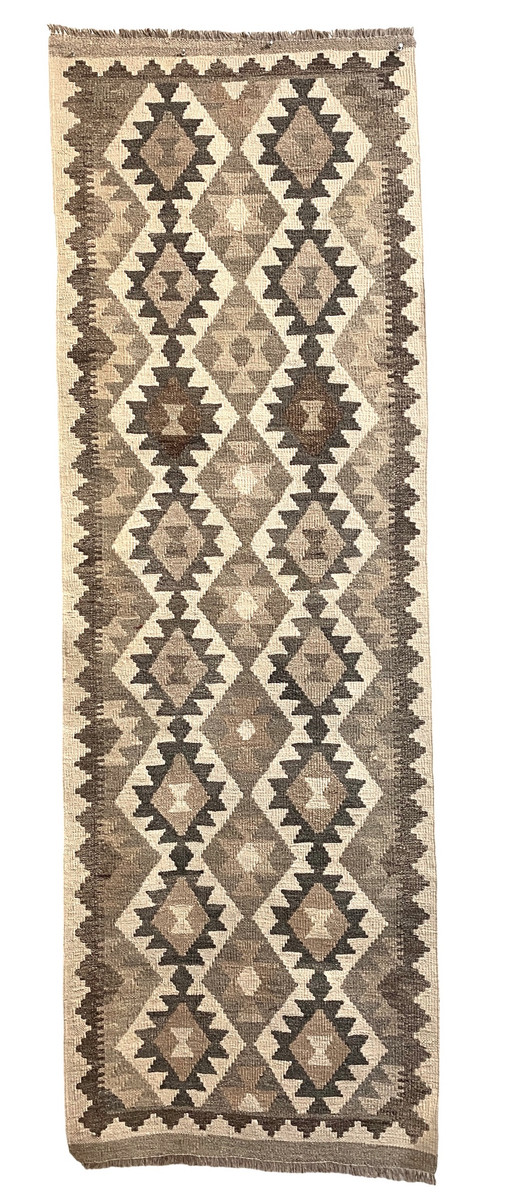 Handwoven wool Kilim rug from Turkmen artisans of Afghanistan. These rugs are a traditional technique with geometric designs. Very sturdy weave structure. Often the maker can use the extra wool from their other weaving to make these rug.  Weaving these rugs is often the only ways for the women weavers to earn an income. These are coming to us from the same group as the Turkmen felted rugs. Ware really happy to be working with these talented and hard work weavers. Colors: natural wool fleece colors- natural,  camel, light grey, medium grey, taupe and dark grey. 