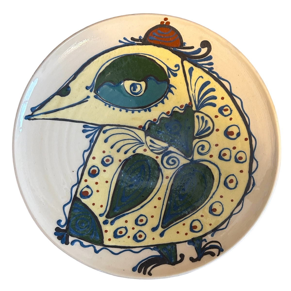 Handmade earthenware platter by Ivan Bobkob. Ivan's food-safe pottery is decorated with bird imagery, a triumphant symbol for Ukrainians representing freedom, rebellion and determination.  Ivan’s pots are painted with birds and Ornek ornamentation, a system of specific symbols embedded with meaning and used by the Crimean Tartar communities. Ornek ornamentation is applied to wood working, weaving, pottery glass, wall paintings and jewelry. (Ornek ornamentation has been placed on the National List of Elements of the Intangible Cultural Heritage of Ukraine.) The cream colored plate has a whimsical bird. Colors: pale yellow, chalky teal, brick, evergreen and charcoal. 