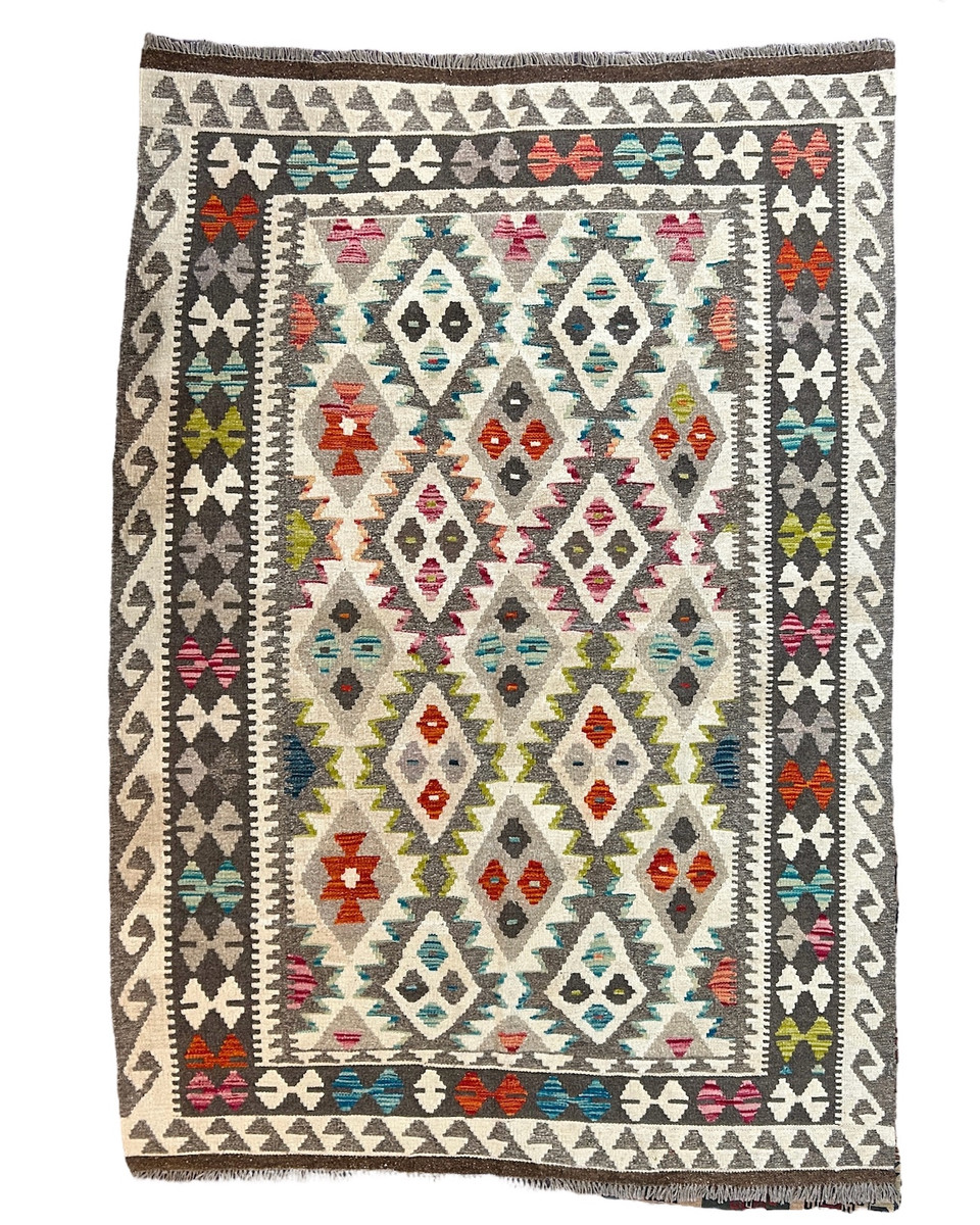 Handwoven wool Kilim rug from Turkmen artisans of Afghanistan. These rugs are a traditional technique with geometric designs and are durable and reversible. With a 'no-waste' approach to weaving, the women incorporate pieces of yarn scraps from other weaving work to create these rugs.  Since the Taliban took control of the country, rug weaving and farming are the only means rural women have to earn an income. This collection comes to us from the same group as the Turkmen felted rugs and we feel honored to represent these talented and hard working weavers. Colors natural fleece colors:cream, grey and heathered brown. And variagated shades of turquoise to teal blue, red, pumpkin, lime and more. 