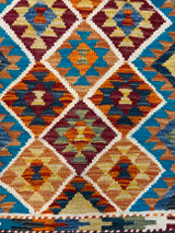 detail . Handwoven wool Kilim rug from Turkmen artisans of Afghanistan. These rugs are a traditional technique with geometric designs and are durable and reversible. With a 'no-waste' approach to weaving, the women incorporate pieces of yarn scraps from other weaving work to create these rugs.  Since the Taliban took control of the country, rug weaving and farming are the only means rural women have to earn an income. This collection comes to us from the same group as the Turkmen felted rugs and we feel honored to represent these talented and hard working weavers. Colors: natural creamy white natural fleece with variegated shades of: deep red, wine, indigo blue, green, pumpkin, turquoise,  pale mustard and dark blue. This small rug works in many spaces in the home and is also beautiful on the wall.