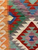 detail Handwoven wool Kilim rug from Turkmen artisans of Afghanistan. These rugs are a traditional technique with geometric designs and are durable and reversible. With a 'no-waste' approach to weaving, the women incorporate pieces of yarn scraps from other weaving work to create these rugs.  Since the Taliban took control of the country, rug weaving and farming are the only means rural women have to earn an income. This collection comes to us from the same group as the Turkmen felted rugs and we feel honored to represent these talented and hard working weavers. Colors: tan, cream, aqua and variageted tones of rich red, purple, greym cobalt blue, turquoise, pumpkin orange, emerald green, and brick. Great long runner rug.