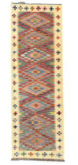 Handwoven wool Kilim rug from Turkmen artisans of Afghanistan. These rugs are a traditional technique with geometric designs and are durable and reversible. With a 'no-waste' approach to weaving, the women incorporate pieces of yarn scraps from other weaving work to create these rugs.  Since the Taliban took control of the country, rug weaving and farming are the only means rural women have to earn an income. This collection comes to us from the same group as the Turkmen felted rugs and we feel honored to represent these talented and hard working weavers. Colors: straw, and variageted tones of red, orange blues, greens, purple, lavender and uchre. Great long runner rug.