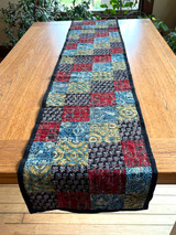 Handmade table runner of block printed fabrics. The fabrics are made with several wooden blocks using the traditional Ajarakh natural dye technique. The fabric is then sewn into a patchwork of various colors and patterns.  Beautiful combination of colors: indigo blue, brick red, black, greenish gold, pale blue grey and more. 1" solid black edging around. The back is solid black with white stitching. This can be reversible 

