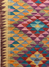 detail Handwoven wool Kilim rug from Turkmen artisans of Afghanistan. These rugs are a traditional technique with geometric designs and are durable and reversible. With a 'no-waste' approach to weaving, the women incorporate pieces of yarn scraps from other weaving work to create these rugs.  Since the Taliban took control of the country, rug weaving and farming are the only means rural women have to earn an income. This collection comes to us from the same group as the Turkmen felted rugs and we feel honored to represent these talented and hard working weavers. Colors: wheat, and variageted tones of turquoise, sky blue, red brick, pumpkin,  chalky greens, purple, lavender and uchre. Great long runner rug.