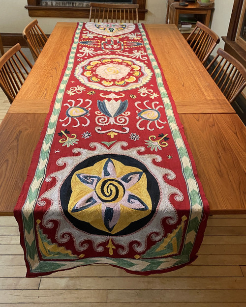 Hand Embroidered Silk Table Runner D Uzbekistan   Embroidery colors: chalky leaf green, pinkish cream, pale bluish cream, chalky pale pink, pale violet cream, pale yellow, Prussian blue, gold, and black that sit atop a silk ground cloth of deep red.