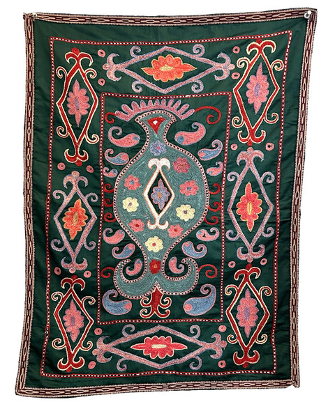 Hand Embroidered Silk Suzani Green Wall Hanging Uzbekistan  Suzani hand stitched wall hanging.  Suzanis are created by the once nomadic people who populated the ancient silk road of Uzbekistan. Suzanis were originally crafted as dowry pieces that a mother would help lovingly create for her daughter’s wedding day. It was believed that the patterns and colors in a suzani held talismanic powers of protection and these powers were magically transferred from the mother into the suzani through the visual impact of her embroidery work. From the studios of Sanjar Nazaroz,  a UNESCO Award of Excellence winner. This size makes a beautiful wall hanging. Shimmering forest green silk ground cloth. Embroidery colors: brick red, chalky teal green, cream, chalky pink, light indigo blue white and black.  There is a 1/2" black and tan woven band around the outside.