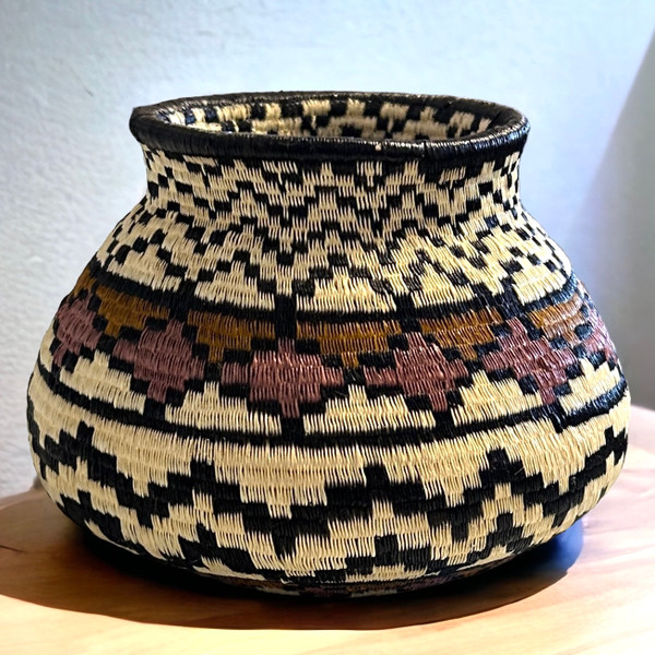 This extra small small fine basket is made from natural palm fronds cut into fine strips. The sturdy basket is woven with a complex technique and with a fine tight pattern. The Wounaan women are considered the finest basket makers in the world. Through basketry they help preserve their culture and in so doing they respect the earth with sustainable harvesting practices. Colors: cream, pinkish tan, brass and charcoal.