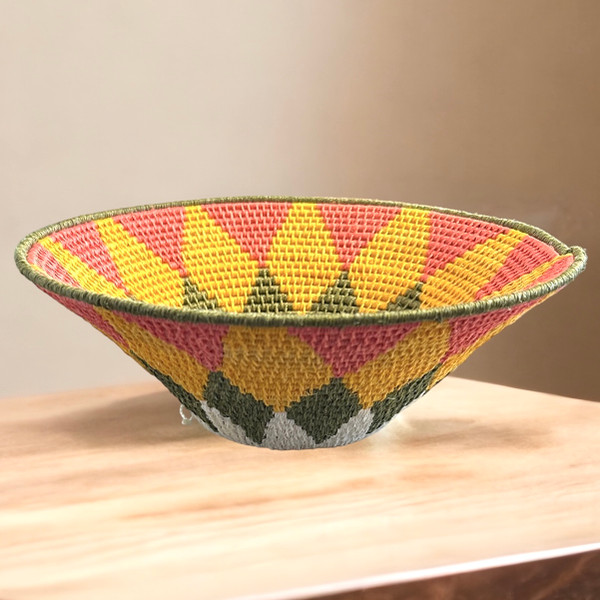 Handwoven medium size fiber basket made with natural sisal from sustainably harvested sources. This is from a small artisan organization that has been working in Eswatini (Swaziland) since 1985. Very sturdy. Beautiful on the table or on the wall. Colors: pink, gold, olive and cream.