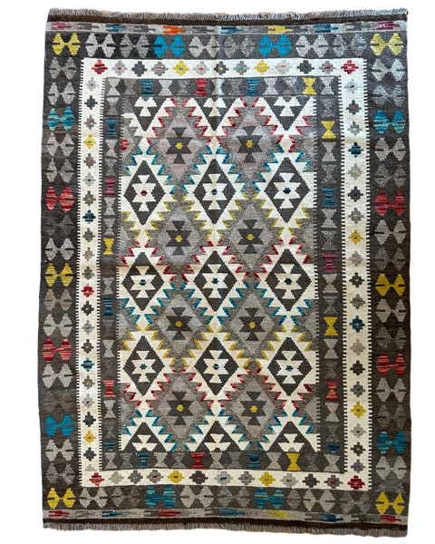 Handwoven wool Kilim rug from Turkmen artisans of Afghanistan. These rugs are a traditional technique with geometric designs and are durable and reversible. With a 'no-waste' approach to weaving, the women incorporate pieces of yarn scraps from other weaving work to create these rugs.  Since the Taliban took control of the country, rug weaving and farming are the only means rural women have to earn an income. This collection comes to us from the same group as the Turkmen felted rugs and we feel honored to represent these talented and hard working weavers. Colors: variegated shades of: grey, bright turquoise, brick red, and mustard, and nat