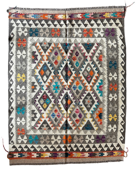 Handwoven wool Kilim rug from Turkmen artisans of Afghanistan. These rugs are a traditional technique with geometric designs and are durable and reversible. With a 'no-waste' approach to weaving, the women incorporate pieces of yarn scraps from other weaving work to create these rugs.  Since the Taliban took control of the country, rug weaving and farming are the only means rural women have to earn an income. This collection comes to us from the same group as the Turkmen felted rugs and we feel honored to represent these talented and hard working weavers. Colors natural fleece colors:cream, light and dark grey. And variegated shades of turquoise, pumpkin, pale gold, rose, purple, deep teal, and taupe. Beautiful on the wall or the floor.
