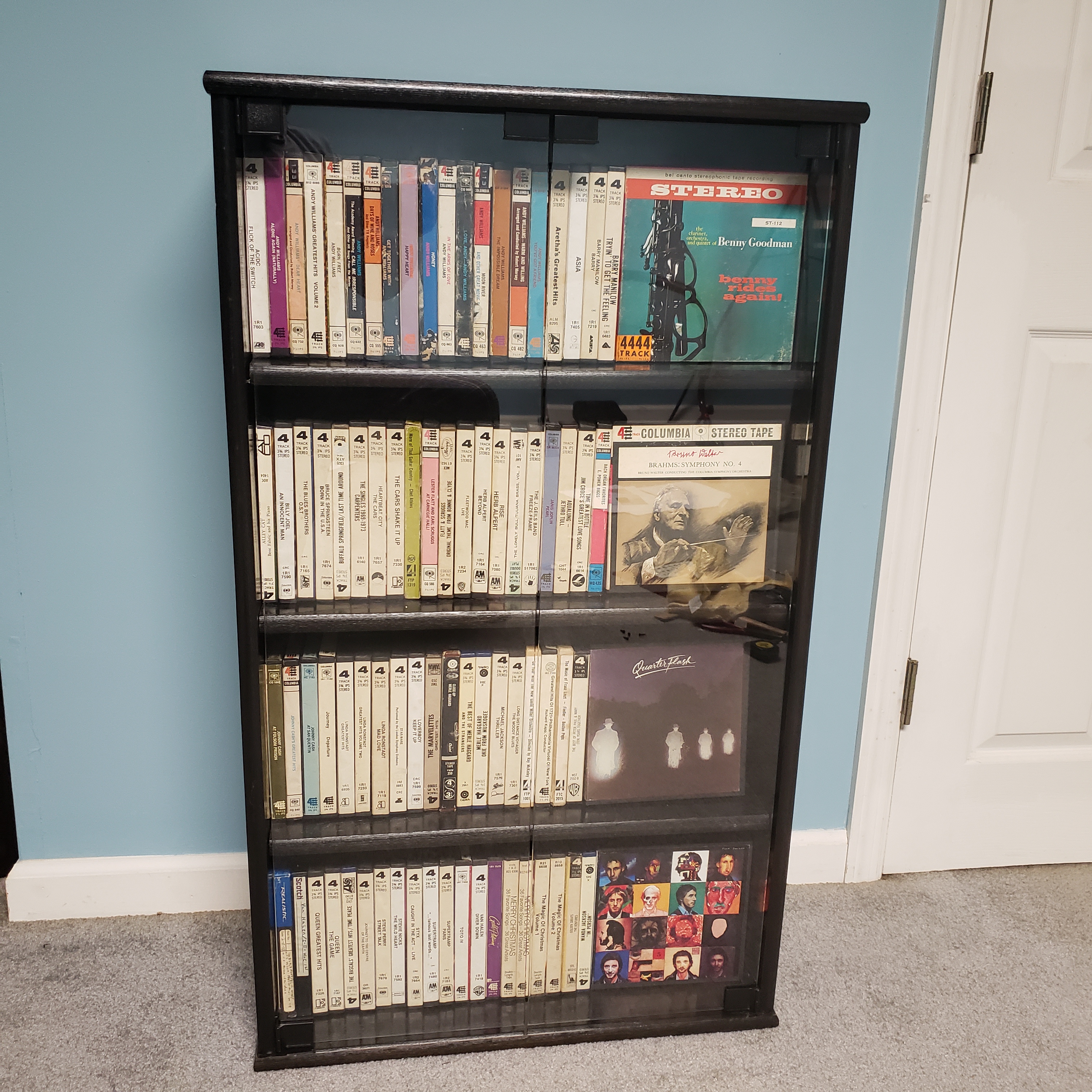 Black reel to reel tape cabinet with clear glass doors.