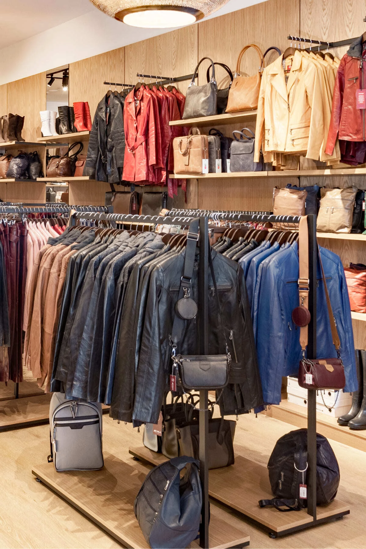 Black Style clothes racks with timber bases, displaying leather jackets and bags in a store