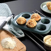 Four-cup non-stick muffin tray with three baked muffins, baking utensils and ingredients on table.