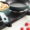 Hand holding black handle of electric griddle with pan of fried rice and lemon slice