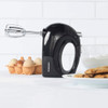 Black electric hand mixer with beaters, eggs, flour and cookies for baking.