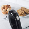 Black electric hand mixer on kitchen counter with eggs and cookies