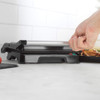 Hand opening black and silver electric grill on kitchen counter