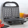 Open black waffle maker on kitchen counter, ready for use.