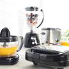 Assorted black kitchen appliances on counter, including juicer, blender, and sandwich maker