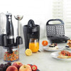Black electric citrus juicer with lid and spout, shown on white background