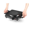 Cleaning a black single hot plate with sponge, showing easy maintenance.
