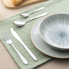 Three-piece silver cutlery set with striped bowl and plate on green napkin