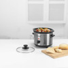 Hand turning dial on silver Progress slow cooker filled with food