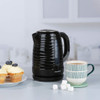 Electric kettle in black with wave pattern, side view showing Progress brand and water level window