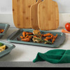 Oven tray with roasted carrots, garlic and herbs on kitchen worktop