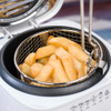 White deep fat fryer with open lid, showing cooked chips in basket