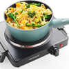 Electric hot plate with pot of pasta and broccoli, hand holding side handle