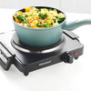 Black single electric hot plate with handles, shown being lifted.