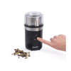 Black electric spice grinder with stainless steel bowl, shown containing whole spices.
