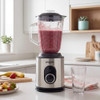 Stainless steel blender with glass jug blending mixed fruit smoothie on kitchen counter