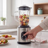 Stainless steel blender with glass jug, filled with fresh fruit, on kitchen counter