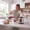 Woman pouring berry smoothie from blender jug into glass, Progress blender on kitchen counter