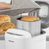 Loaf of bread being lifted from white Progress bread maker in kitchen