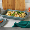 Green non-stick roasting tins with roasted vegetables on kitchen worktop